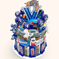 CandyCakeExplosion blue college candy cake featuring assorted chocolates, Airheads, and lollipops with mascot topper.