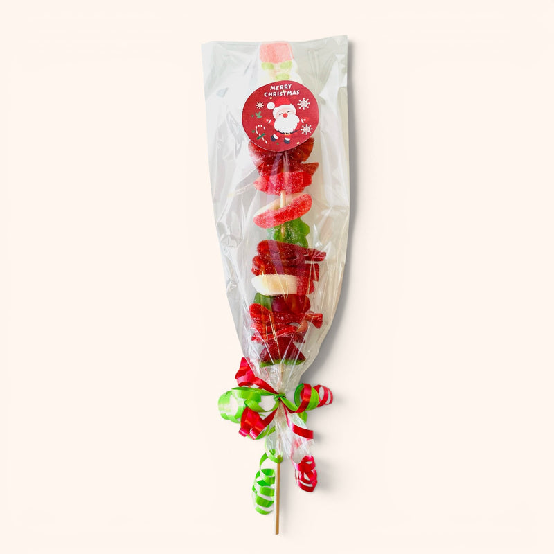 CandyCakeExplosion Christmas candy kabob with red, green, and white gummies and marshmallows in a festive wrapper.
