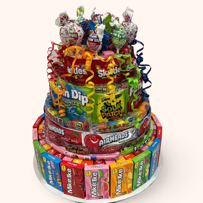 CandyCakeExplosion jumbo multi-tiered non-chocolate candy cake featuring assorted gummies, lollipops, and fruit sweets.