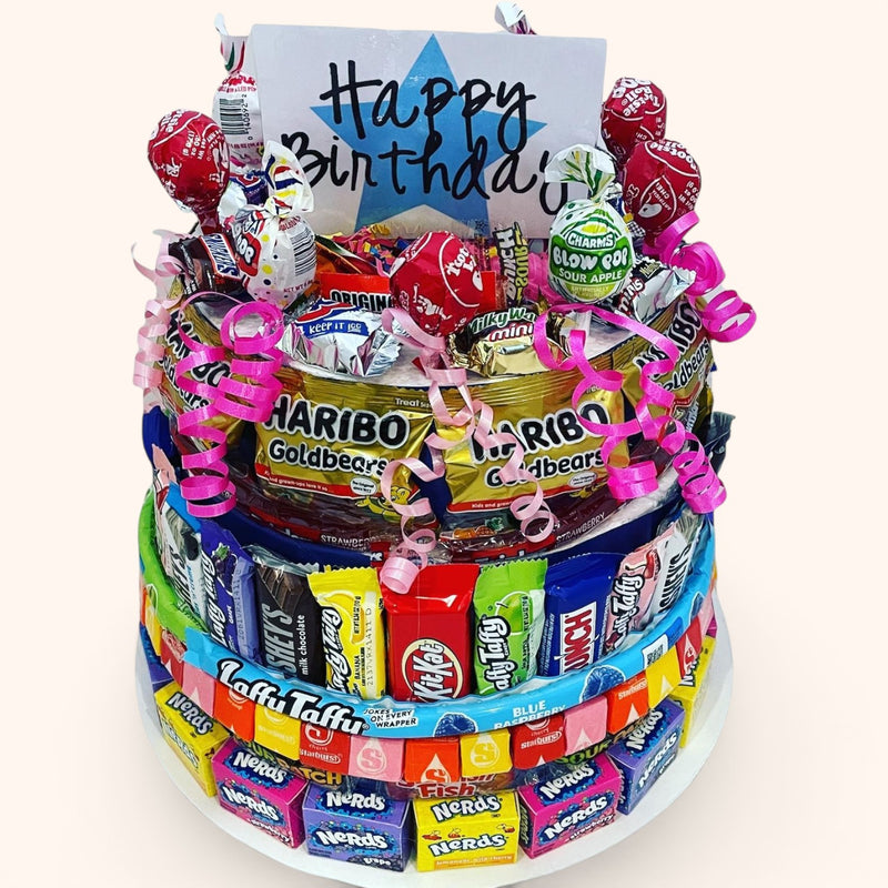 CandyCakeExplosion large multi-tiered birthday candy cake featuring assorted chocolates, Haribo gummies, and lollipops.
