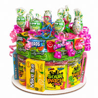 CandyCakeExplosion medium tiered sour candy cake featuring Sour Patch Kids, Laffy Taffy, and Blow Pops with pink bows.