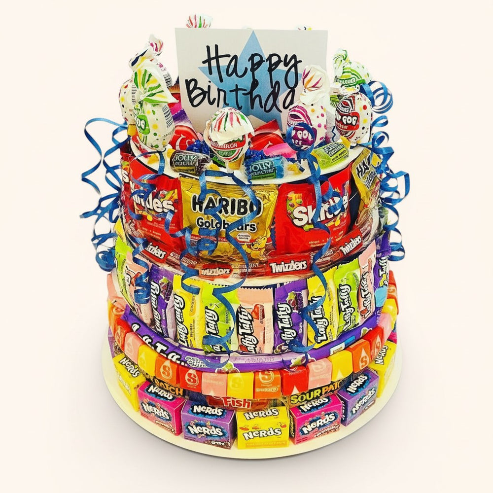 CandyCakeExplosion three-tier birthday candy cake decorated with assorted colorful sweets and a Happy Birthday sign.
